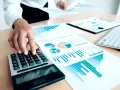 Un trésorier CSE utilise une calculatrice et des graphiques pour analyser les finances.