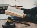 Un avocat étudie le livre de droit, cherchant la définition de l'obligation de résultat selon l'article 1231-1 du Code civil. Balance de la justice et marteau de juge en arrière-plan.