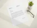 Une lettre de départ à la retraite est posée sur un bureau, à côté de lunettes et d'une plante.