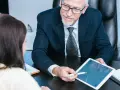 Un homme d'affaires expérimenté partage son expertise CSE en montrant un calendrier sur une tablette à une collègue.