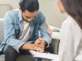 Un homme en arrêt maladie psychiatre reçoit un soutien réconfortant d'une thérapeute lors d'un contrôle.