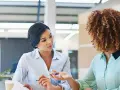Deux femmes discutent au bureau. L'une semble expliquer les 5 obligations de l'employeur à l'autre.