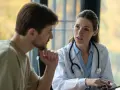 Médecin expliquant un plan de traitement à un patient lors d'une visite de pré-reprise. Le délai est respecté.