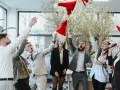 Des employés lancent des bonnets de Père Noël en l'air, célébrant joyeusement leur repas de Noël d'entreprise.