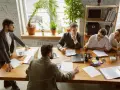 Une équipe discute autour d'une table dans un bureau lumineux, illustrant le concept de **flex office** : collaboration et adaptabilité.
