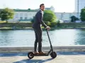 Homme en costume sur trottinette électrique, profitant de la liberté de mouvement. Une nouvelle façon de gérer la loi distance travail domicile.