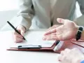 Une personne signe un contrat, discutant des conditions d'emploi avec un interlocuteur.