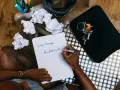 Un homme écrit "Au revoir..." sur une feuille, peut-être un mail de démission. Des brouillons froissés et des clés sont à proximité.