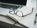 Lunettes sur un carnet ouvert, stylo et ordinateur portable. Idéal pour un congé formation professionnelle dans le privé, pour planifier son avenir.