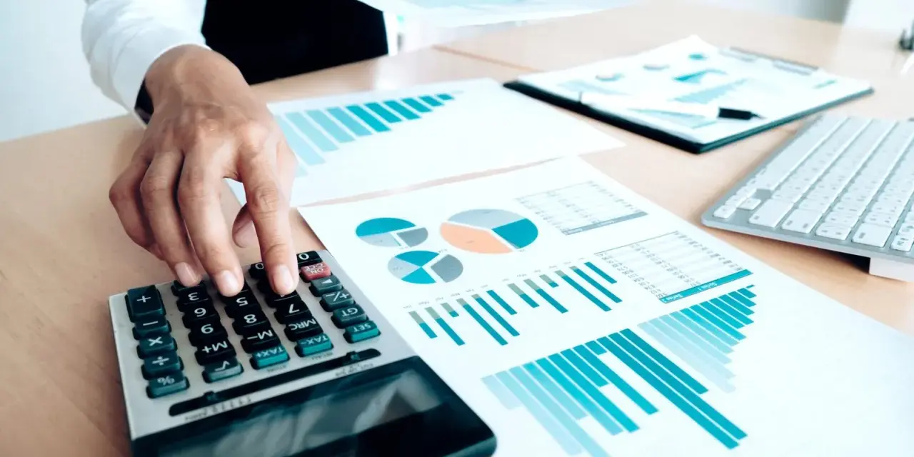 Un trésorier CSE utilise une calculatrice et des graphiques pour analyser les finances.