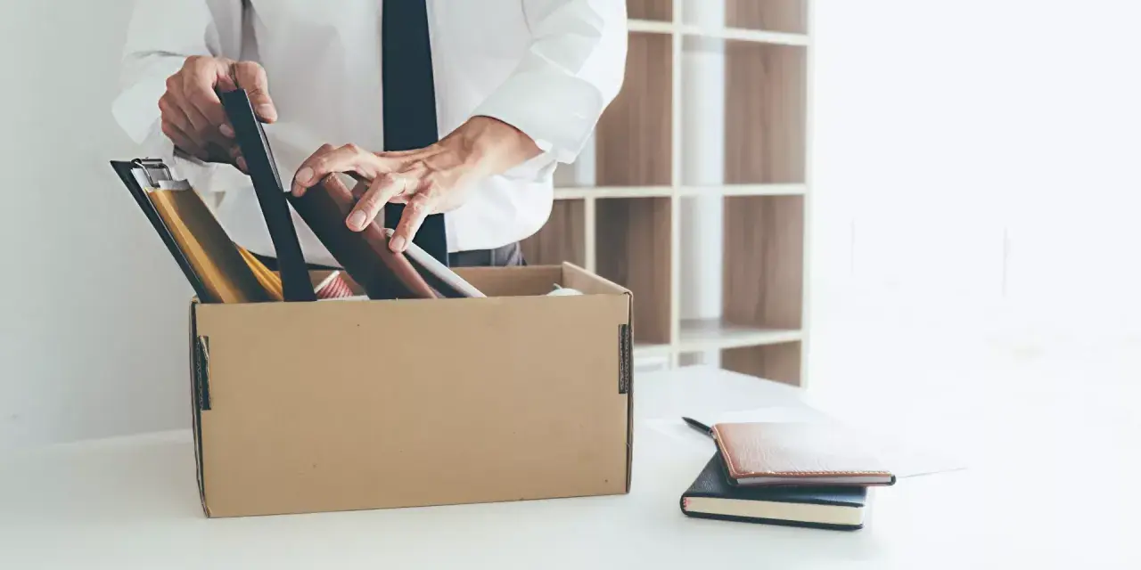 Un homme met ses affaires dans un carton, une scène évoquant un licenciement après arrêt maladie longue durée.