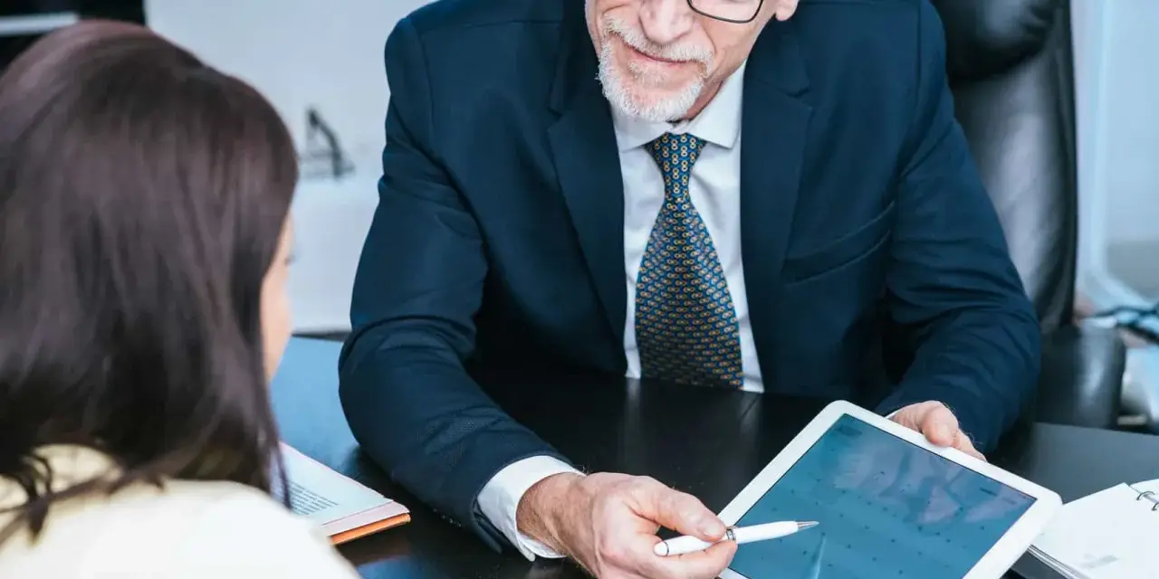 Un homme d'affaires expérimenté partage son expertise CSE en montrant un calendrier sur une tablette à une collègue.