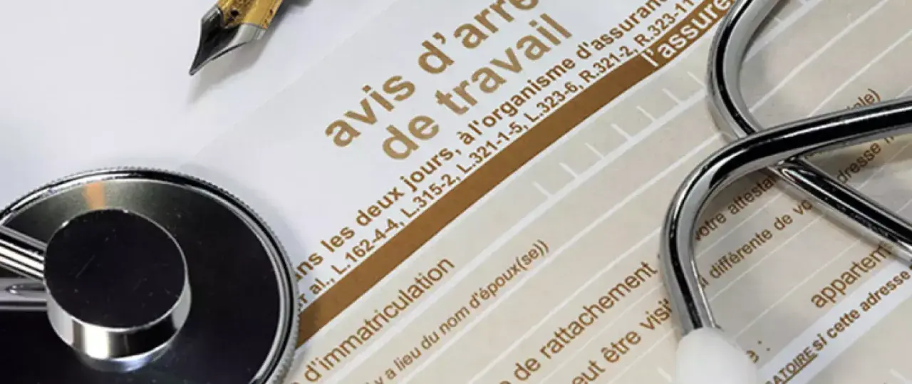 Un stéthoscope et un stylo sur un avis d'arrêt de travail, évoquant une maladie professionnelle pour une aide à domicile.