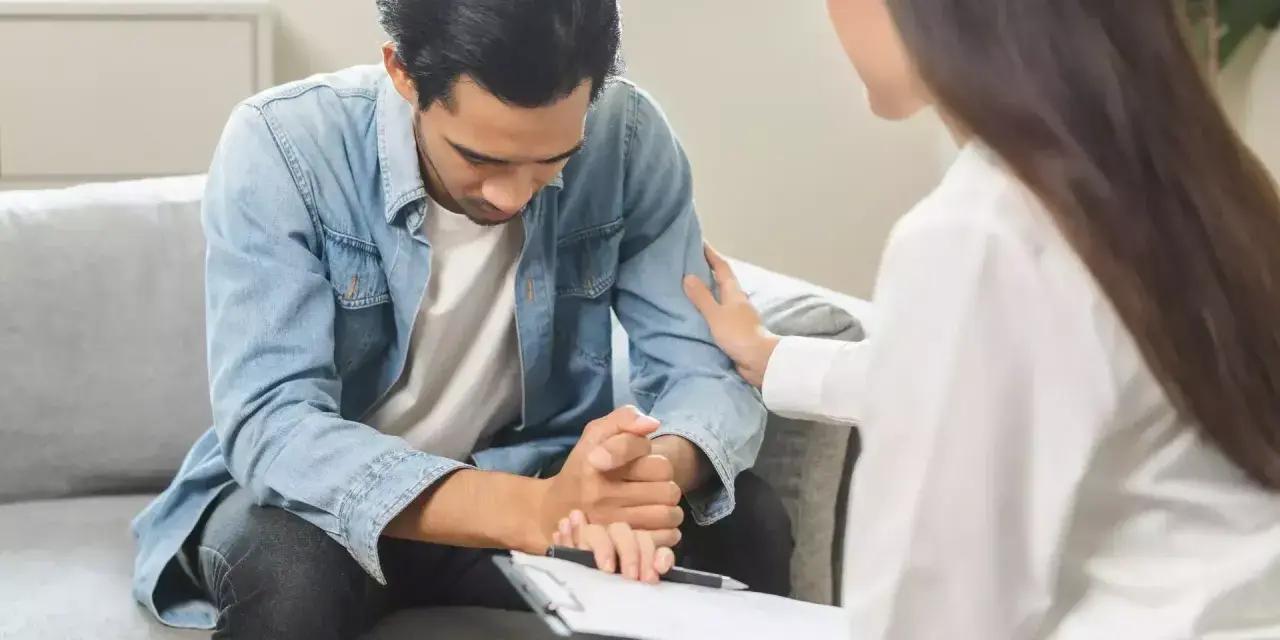 Un homme en arrêt maladie psychiatre reçoit un soutien réconfortant d'une thérapeute lors d'un contrôle.