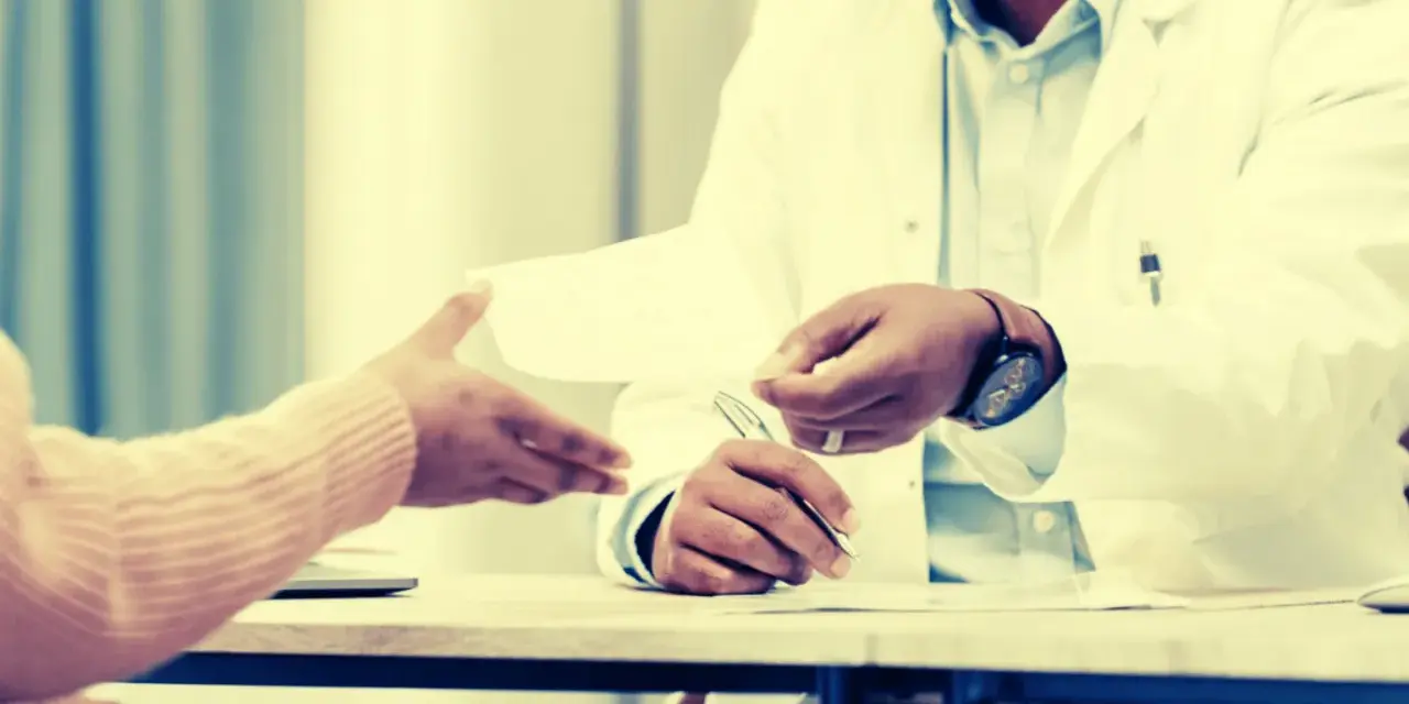Un médecin remet un document, peut-être une suspension des indemnités journalières par le médecin conseil, à un patient.