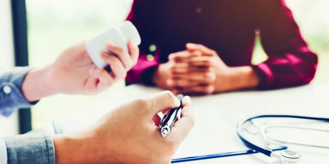 Un médecin donne des médicaments à un patient lors d'une visite de reprise obligatoire.