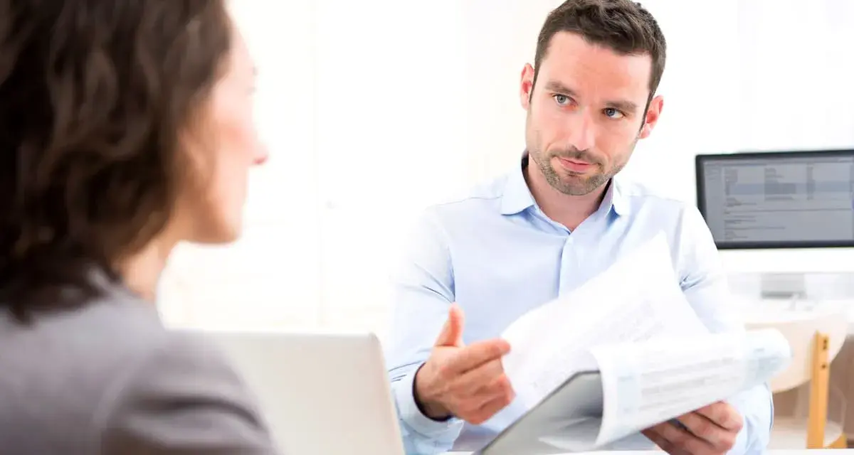 Un homme explique un document à une femme, discutant peut-être de la VAE et de l'obligation employeur.