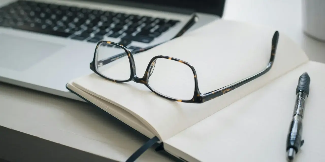 Lunettes sur un carnet ouvert, stylo et ordinateur portable. Idéal pour un congé formation professionnelle dans le privé, pour planifier son avenir.
