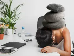 Une femme accablée par des pierres sur la tête, symbolisant le poids du harcèlement au travail. Le référent harcèlement CSE heures de délégation est dépassé.