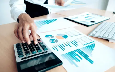 Un trésorier CSE utilise une calculatrice et des graphiques pour analyser les finances.