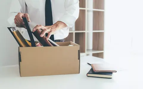 Un homme met ses affaires dans un carton, une scène évoquant un licenciement après arrêt maladie longue durée.
