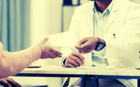 Un médecin remet un document, peut-être une suspension des indemnités journalières par le médecin conseil, à un patient.