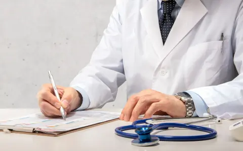 Médecin en blouse blanche rédigeant un rapport, stéthoscope à proximité. Un signalement médecine du travail est en cours.