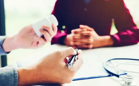 Un médecin donne des médicaments à un patient lors d'une visite de reprise obligatoire.