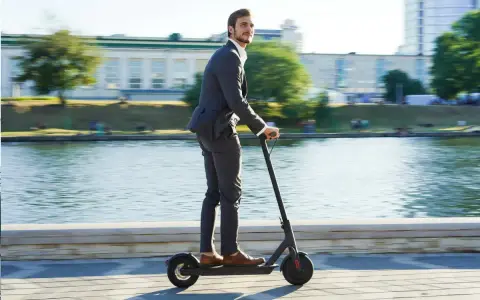 Homme en costume sur trottinette électrique, profitant de la liberté de mouvement. Une nouvelle façon de gérer la loi distance travail domicile.