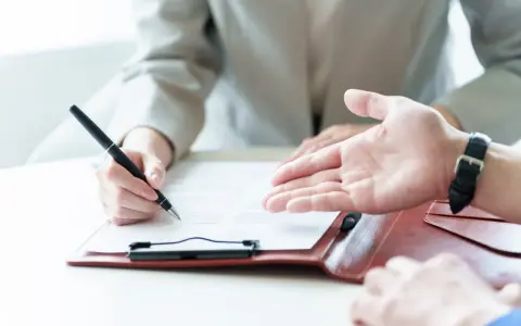 Une personne signe un contrat, discutant des conditions d'emploi avec un interlocuteur.