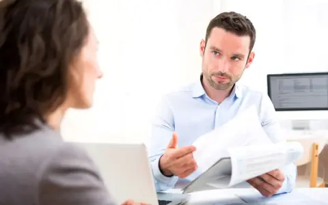 Un homme explique un document à une femme, discutant peut-être de la VAE et de l'obligation employeur.