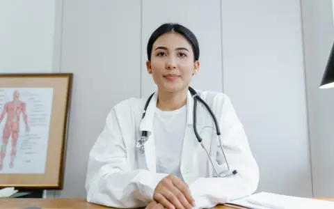 Médecine du travail : ce qu'il ne faut pas dire. Une doctoresse au regard bienveillant, stéthoscope autour du cou, devant un schéma anatomique.