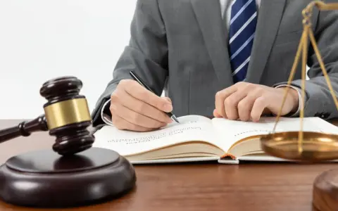 Un avocat en costume écrit dans un livre de droit, marteau de juge et balance de la justice à proximité. Une scène symbolisant l'entrave au CSE.