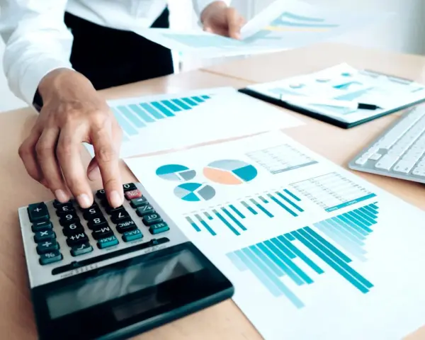 Un trésorier CSE utilise une calculatrice et des graphiques pour analyser les finances.