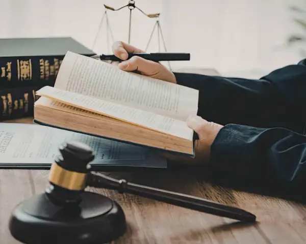 Un avocat étudie le livre de droit, cherchant la définition de l'obligation de résultat selon l'article 1231-1 du Code civil. Balance de la justice et marteau de juge en arrière-plan.
