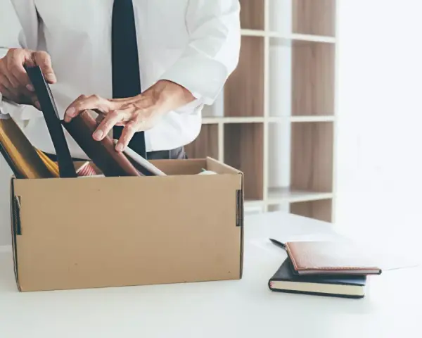 Un homme met ses affaires dans un carton, une scène évoquant un licenciement après arrêt maladie longue durée.