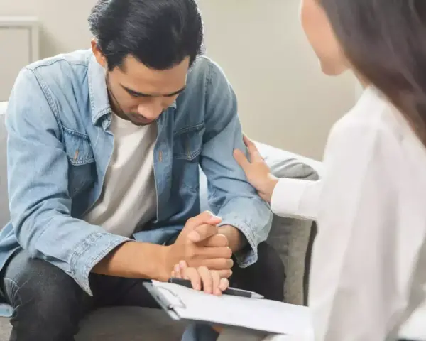Un homme en arrêt maladie psychiatre reçoit un soutien réconfortant d'une thérapeute lors d'un contrôle.