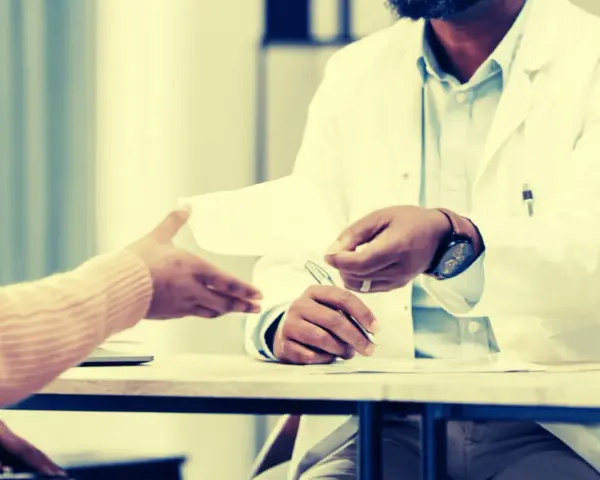 Un médecin remet un document, peut-être une suspension des indemnités journalières par le médecin conseil, à un patient.