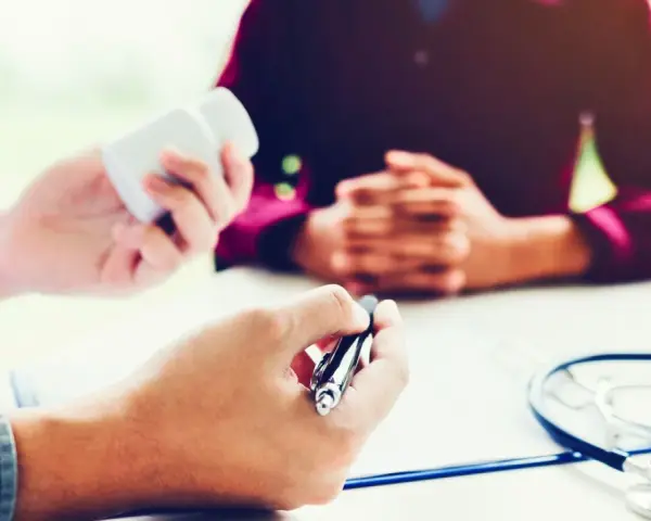 Un médecin donne des médicaments à un patient lors d'une visite de reprise obligatoire.