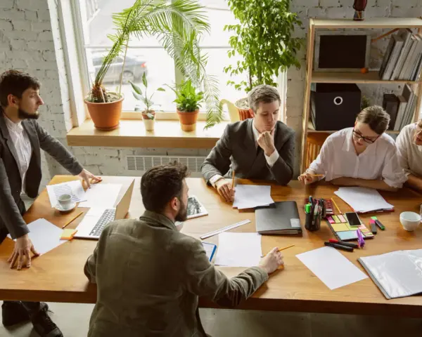 Une équipe discute autour d'une table dans un bureau lumineux, illustrant le concept de **flex office** : collaboration et adaptabilité.