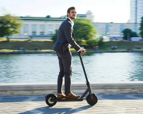 Homme en costume sur trottinette électrique, profitant de la liberté de mouvement. Une nouvelle façon de gérer la loi distance travail domicile.