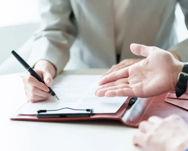 Une personne signe un contrat, discutant des conditions d'emploi avec un interlocuteur.