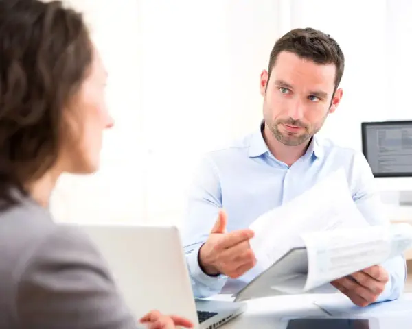 Un homme explique un document à une femme, discutant peut-être de la VAE et de l'obligation employeur.