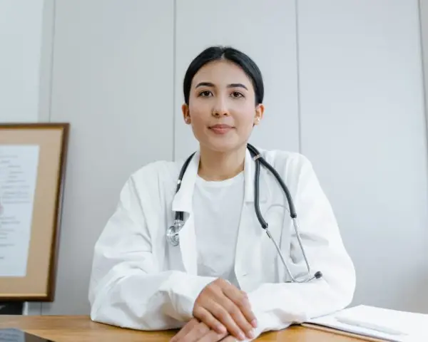 Médecine du travail : ce qu'il ne faut pas dire. Une doctoresse au regard bienveillant, stéthoscope autour du cou, devant un schéma anatomique.