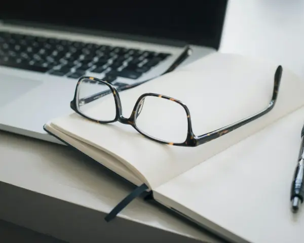 Lunettes sur un carnet ouvert, stylo et ordinateur portable. Idéal pour un congé formation professionnelle dans le privé, pour planifier son avenir.