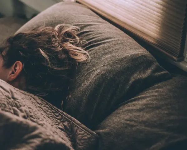 Une personne dort, peut-être suite à un licenciement pour absence injustifiée, se demandant si elle a droit au chômage.