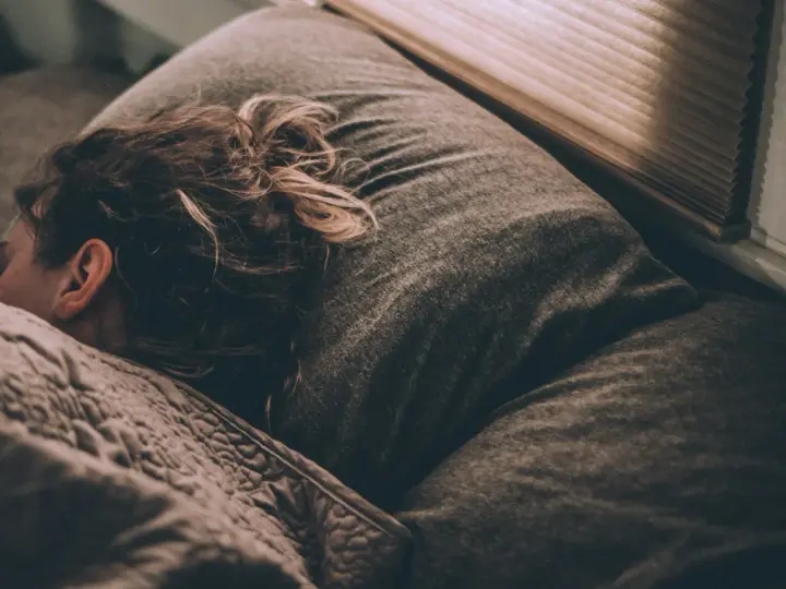 Une personne dort, peut-être suite à un licenciement pour absence injustifiée, se demandant si elle a droit au chômage.