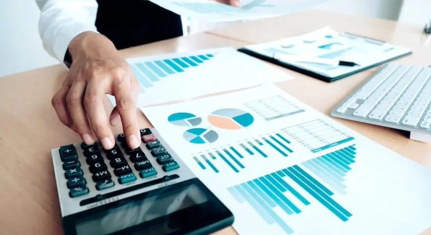 Un trésorier CSE utilise une calculatrice et des graphiques pour analyser les finances.