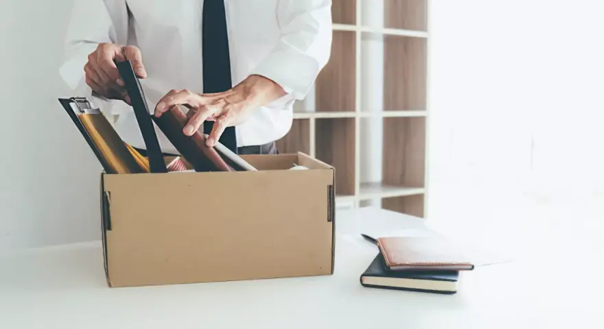 Un homme met ses affaires dans un carton, une scène évoquant un licenciement après arrêt maladie longue durée.