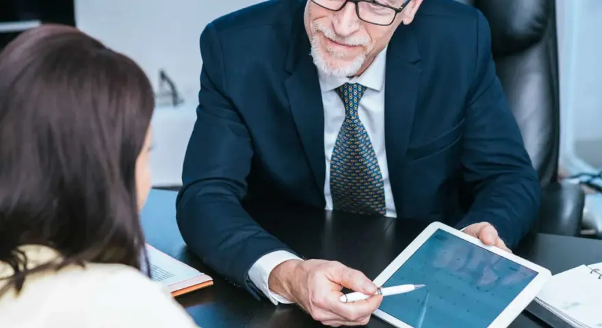 Un homme d'affaires expérimenté partage son expertise CSE en montrant un calendrier sur une tablette à une collègue.